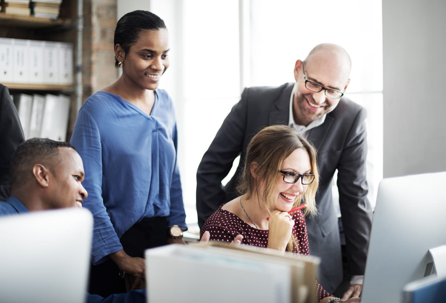Smiling people looking at computer monitor